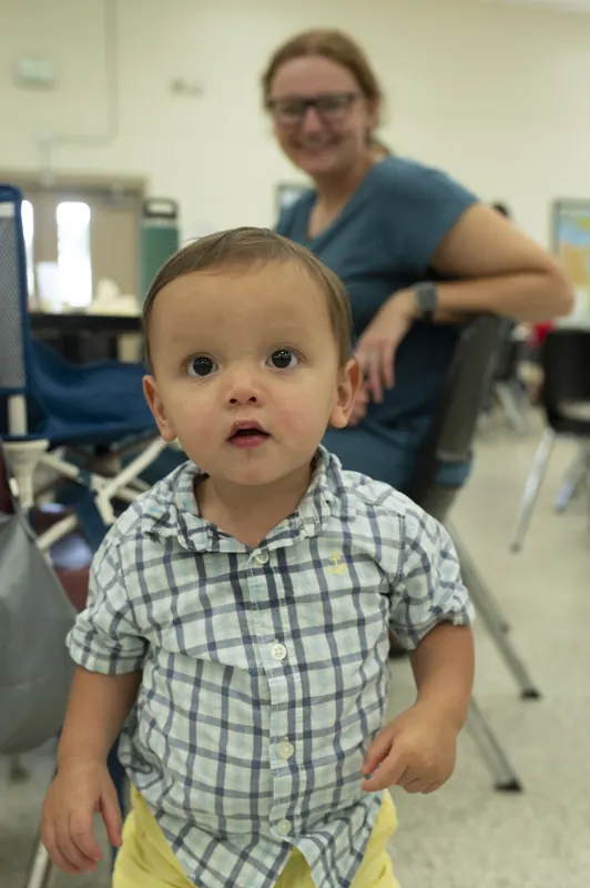 A toddler at a parish gathering, his mother behind him