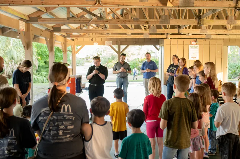 Families gathered in prayer at a parish picnic