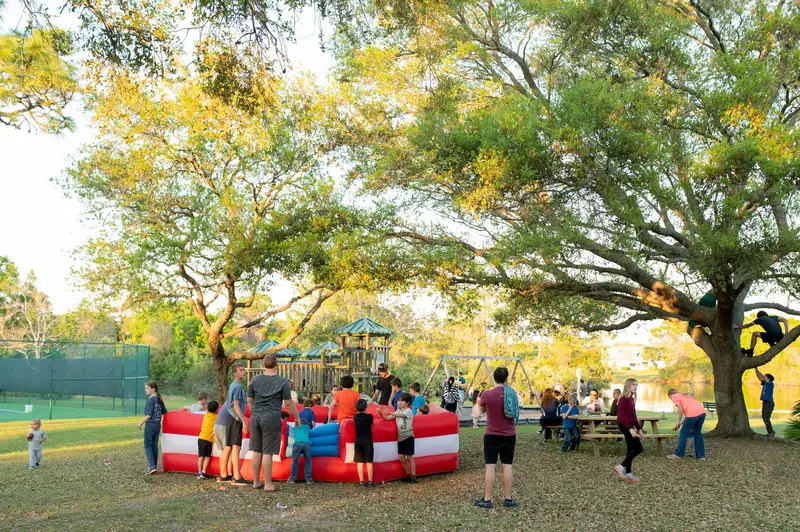Children and parents playing under the oaks at a parish park